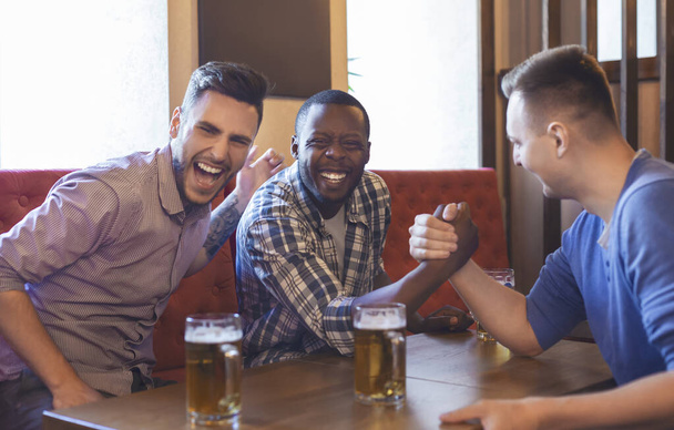 Армрестлинг. Мужские друзья веселятся в баре
 - Фото, изображение