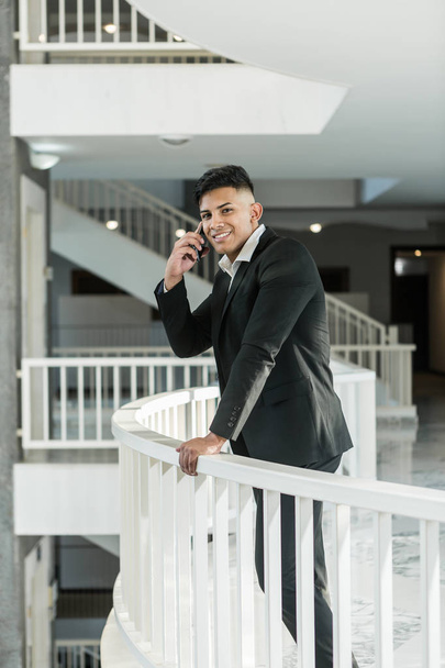 Χαμογελαστή εθνική διευθυντής απαντώντας τηλεφωνική κλήση στο μπαλκόνι - Φωτογραφία, εικόνα