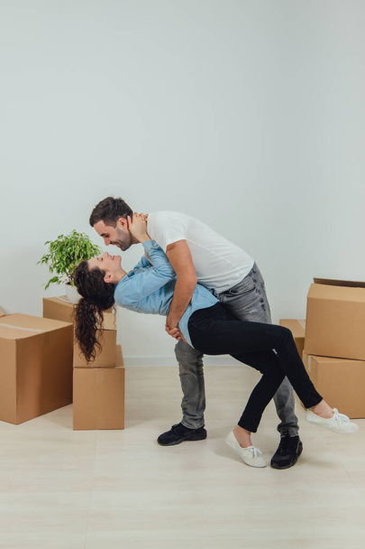 Man and woman in new apartment, surrounded by carton boxes, dancing, being in the seventh heaven to change location. - Fotografie, Obrázek