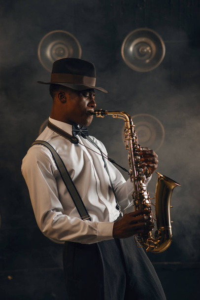 Аріканський джазман грає на саксофоні на сцені з прожекторами. - Фото, зображення