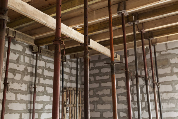 Ansicht der Holzschalung mit Metallhalterungen, die mit Überlappungen zwischen den Fußböden in einem im Bau befindlichen Landhaus aus Schaumstoffblock gefüllt wird - Foto, Bild