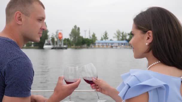 rest on water, male and woman drinking wine on yacht, happy couple drink red beverage in background sea - Materiał filmowy, wideo