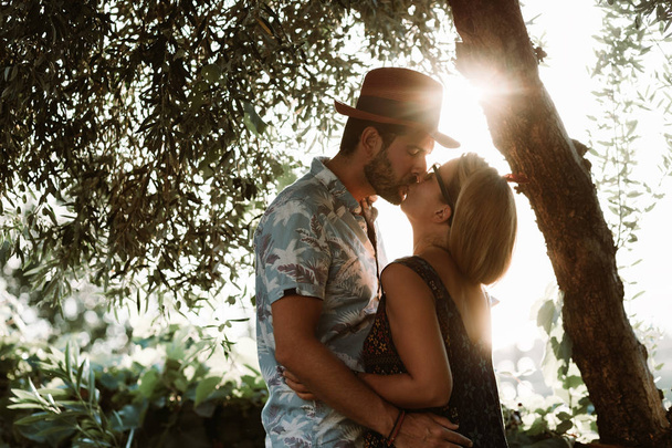 Para zakochanych całujących się w ogrodzie o zachodzie słońca - Zdjęcie, obraz