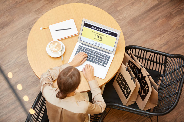 Jonge vrouw zitten aan de tafel en met behulp van laptop computer gaat kopen online in cafe - Foto, afbeelding