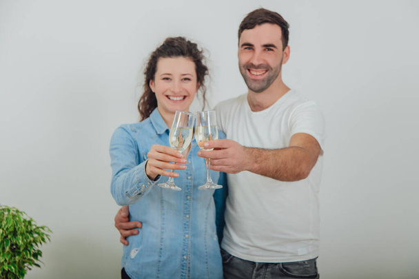 Blurred shot of charming copule standing with glasses of champange, celebrating their move into new apartment, smiling. - Zdjęcie, obraz