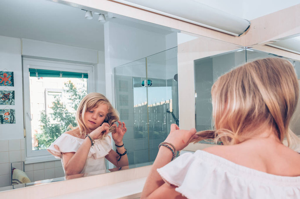 little kid in the bathroom playing with long blond hair - Photo, Image