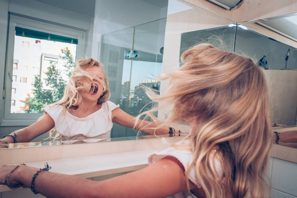 encantadora menina loira se divertindo com cabelo loiro longo enquanto gritando de alegria
 - Foto, Imagem
