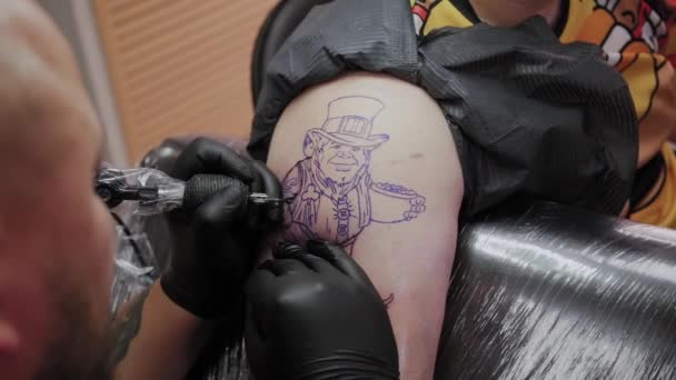Artista profesional del tatuaje hace un tatuaje en el brazo de un hombre
. - Metraje, vídeo