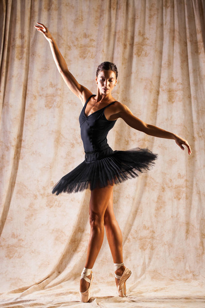 Full body portrait. Russian ballerina in a black dancing suit is - Fotó, kép