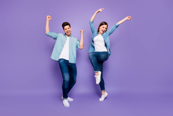 Full size photo of funny crazy spouses feel lucky celebrate victory on honeymoon weekends raise fists scream yeah wear good-looking outfit sneakers isolated over violet purple color background - Photo, image