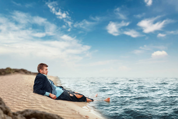 Businessman in torn suit resting on the beach on lost island. Business risk, collapse or bankruptcy concept - Фото, зображення