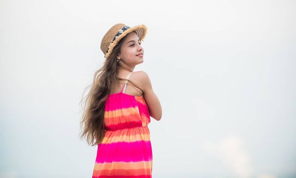 Cute girl in summer dress and hat outdoors sky background. Happy vacation. Happy childhood. Enjoying relax. Child happy small girl. Free and carefree. Good vibes. Happy international childrens day - Φωτογραφία, εικόνα