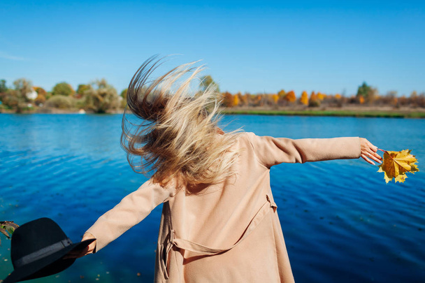 秋の気分。若い女性が川に飛び乗って楽しんでいます。秋を歓迎する腕を上げる女の子 - 写真・画像