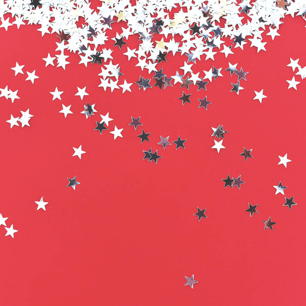 Silberne Sterne Konfetti auf rotem Hintergrund.  - Foto, Bild