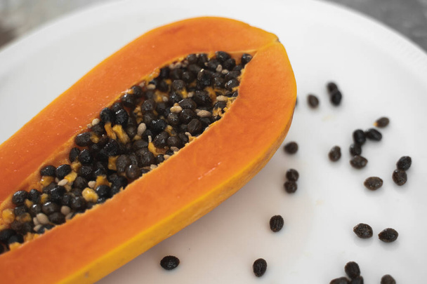 Half cut ripe papaya with seed on a white plate. Slices of sweet papaya with a white background. Halved papayas. Healthy exotic fruits. Vegetarian food. - Foto, Imagem