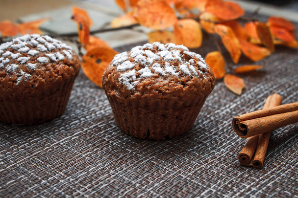 Шоколадные кексы с вкусной начинкой из яблок и сахаром на фоне осенних листьев и яблок
 - Фото, изображение