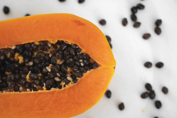 Half cut ripe papaya with seed on a white plate. Slices of sweet papaya with a white background. Halved papayas. Healthy exotic fruits. Vegetarian food. - Photo, image