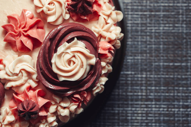 Różowy tort z kremowymi kwiatami na ciemnym tle - Zdjęcie, obraz