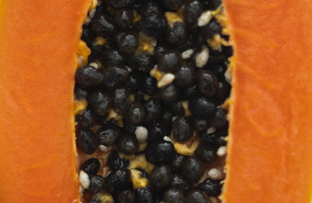 Half cut ripe papaya with seed on a white plate. Slices of sweet papaya with a white background. Halved papayas. Healthy exotic fruits. Vegetarian food. - Foto, afbeelding