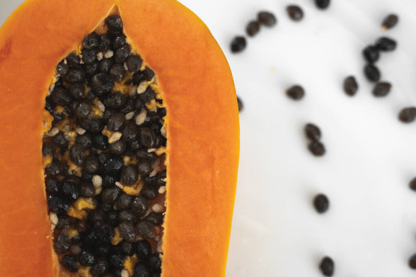 Half cut ripe papaya with seed on a white plate. Slices of sweet papaya with a white background. Halved papayas. Healthy exotic fruits. Vegetarian food. - Fotografie, Obrázek