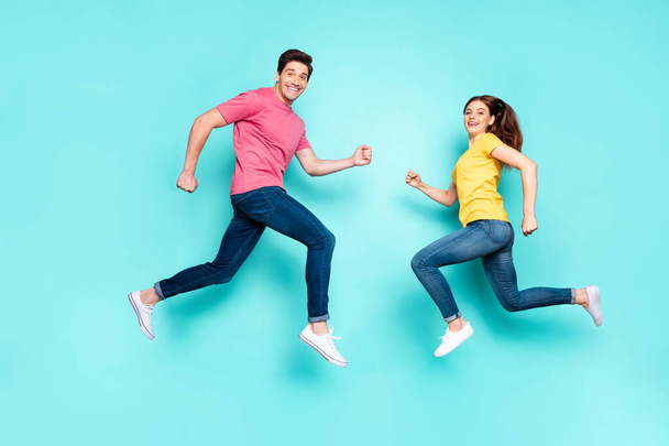 Full length body size profile side view of nice attractive sporty cheerful couple running jumping in air having fun holiday spring isolated over bright vivid shine vibrant green turquoise background - Fotoğraf, Görsel