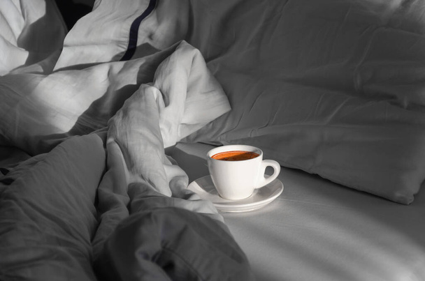 Morning coffee in bed. Cup of coffee on the bed in the room with a lot of natural sunlight. Enjoying the little things. Morning concept - Photo, Image