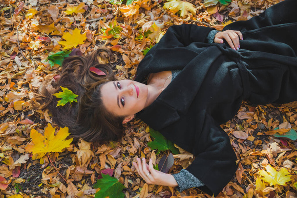 vrouw liggend op de grond in de herfst gele bladeren - Foto, afbeelding