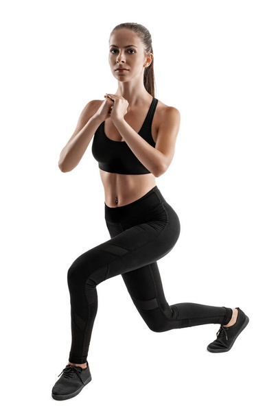Brunette woman in black leggings, top and sneakers is posing isolated on white. Fitness, gym, healthy lifestyle concept. Full length. - Fotoğraf, Görsel