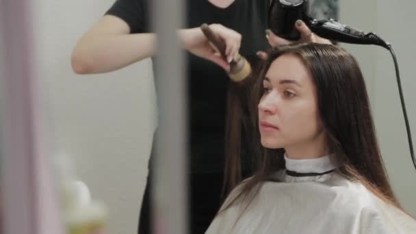 Dívka kadeřník suší vlasy na klienta s fénem na kadeřnictví. - Záběry, video