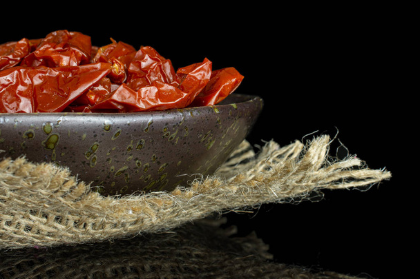 Dry red cherry tomato isolated on black glass - Fotó, kép