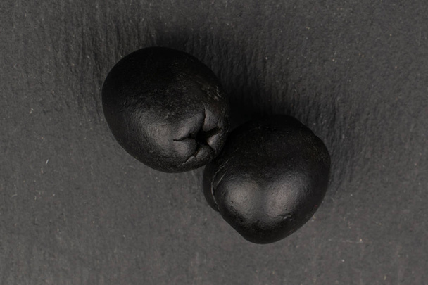 Aceituna negra en vinagre sobre piedra gris
 - Foto, Imagen
