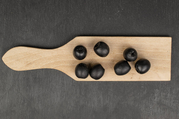 Pickled black olive on grey stone - Zdjęcie, obraz