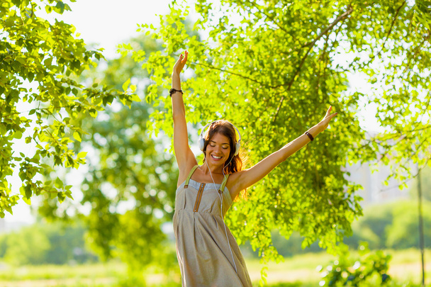 Happy girl wearing hedphones outdoors - Photo, Image