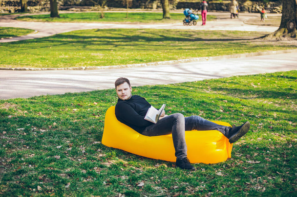 concepto de lectura de libros. hombre en parque de la ciudad en colchón inflable
 - Foto, imagen