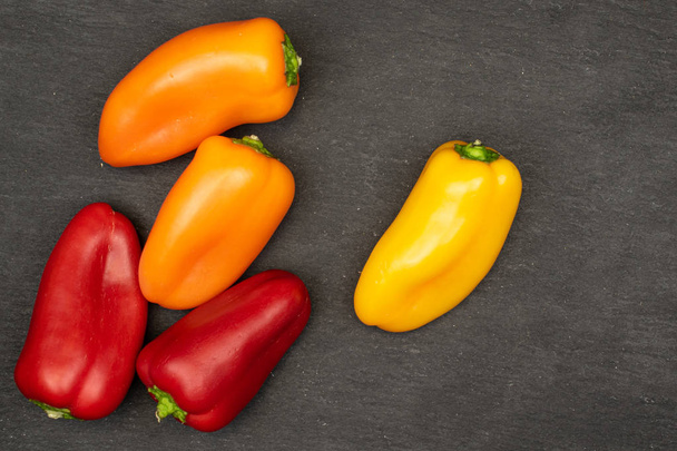 Group of five whole fresh pepper flatlay on grey stone - 写真・画像