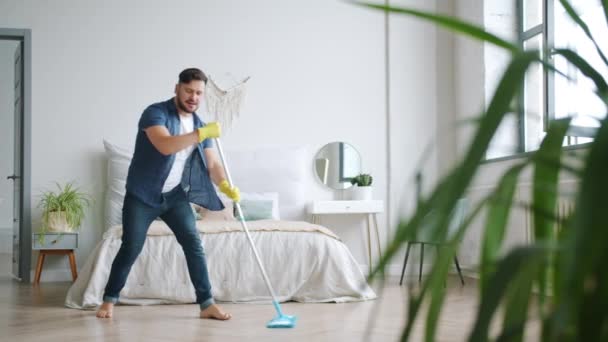 Crazy person having fun at home singing in mop dancing washing floor alone - Felvétel, videó
