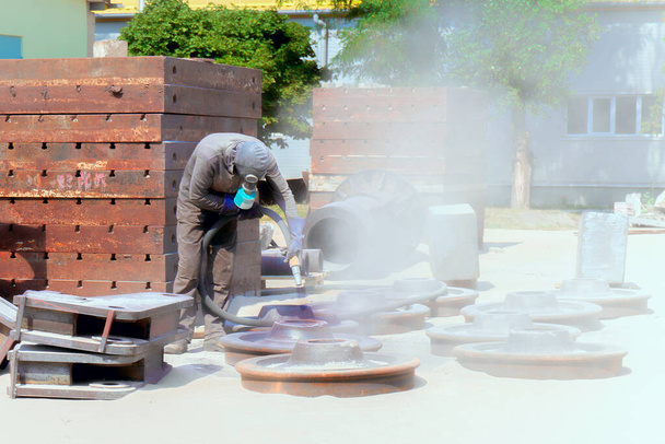 Пескоструйная обработка на промышленном предприятии, рабочий вырубает оксид
  - Фото, изображение