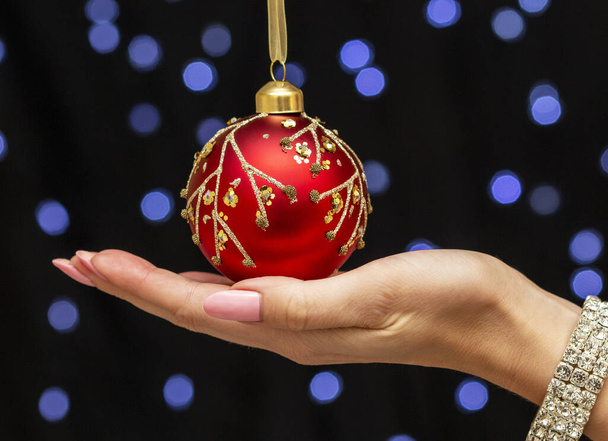 Güzel, zarif bir kadın eli etkileyici bir kırmızı Noel balosu tutuyor. - Fotoğraf, Görsel
