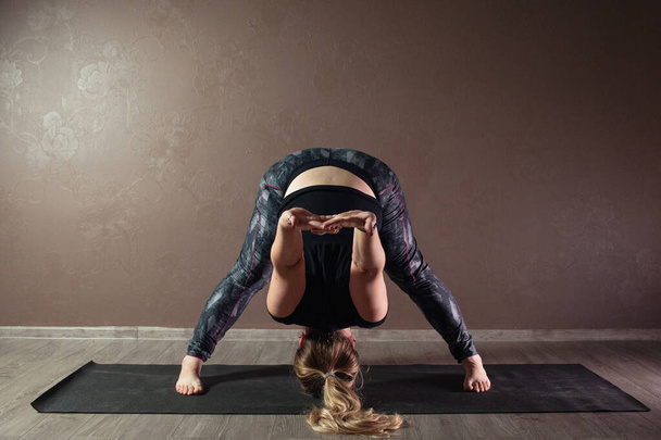 Jovem desportiva atraente mulher praticando ioga, meditando em pose de ioga, trabalhando fora, vestindo sportswear, comprimento total interior, estúdio de ioga marrom
 - Foto, Imagem