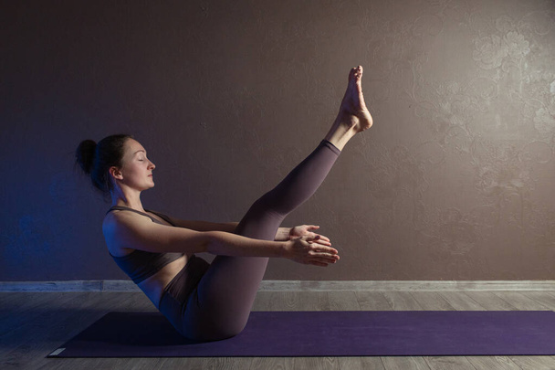 Giovane donna attraente sportiva che pratica yoga, meditando in posa yoga, lavorando fuori, indossando abbigliamento sportivo, indoor full length, studio di yoga marrone
 - Foto, immagini