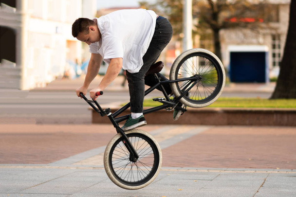 The guy on the BMX bike performs a trick on the front wheel. - Photo, Image