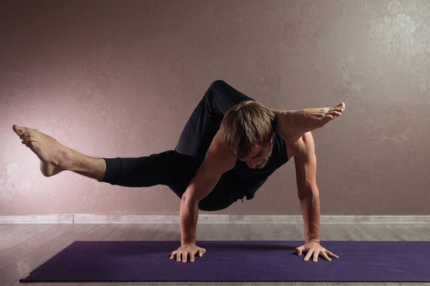 Jeune homme sportif pratiquant le yoga, méditant dans la pose Half Lotus, faisant de l'exercice, portant des vêtements de sport, intérieur pleine longueur, studio de yoga brun
 - Photo, image
