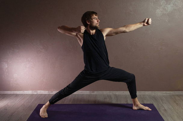Fiatal sportos férfi jógázik, meditál jóga pózban, edz, sportruházatot visel, beltéri teljes hossz, barna jóga stúdió - Fotó, kép