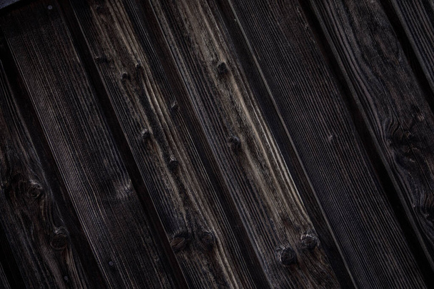 Темно-коричневый деревянный фон. Натуральные деревянные доски насыщены темным маслом. Доски с узлами и гвоздями расположены под углом
 - Фото, изображение