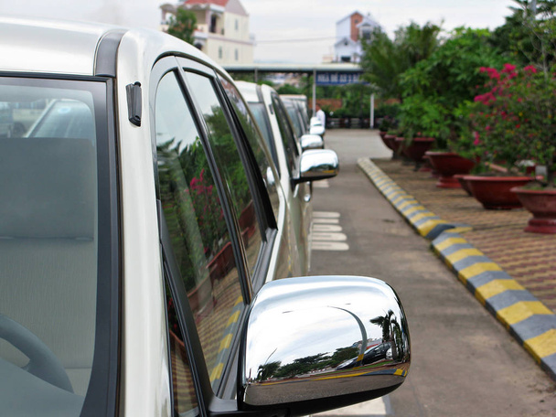 Taxi 's staan klaar. Zicht op de achteruitkijkspiegels. Mooie bloemen in bloempotten staan rechts opgesteld. Auto 's bevinden zich op het vliegveld in Vietnamees op het eiland Phu Quoc. - Foto, afbeelding