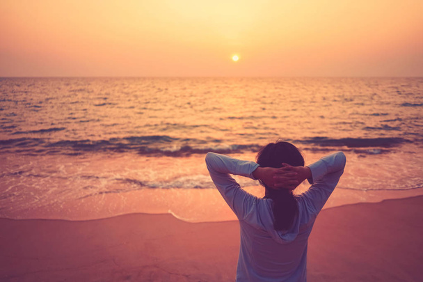 Copy space of woman rise hand up on sunset sky at beach and island background. - Photo, Image