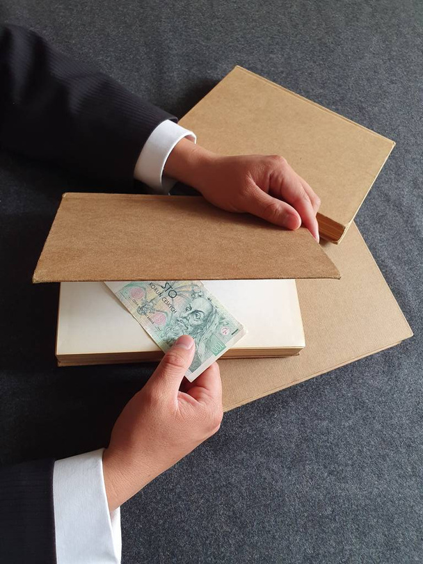 Hände eines Geschäftsmannes mit tschechischem Geld und Büchern auf dem Tisch  - Foto, Bild