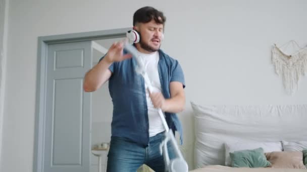 Slow motion of funny man having fun with vacuum cleaner then cleaning carpet - Záběry, video