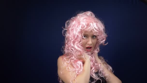 cute girl in a pink curly wig in a black leather corset flirts looking at the camera. adventures of strange people. - Footage, Video