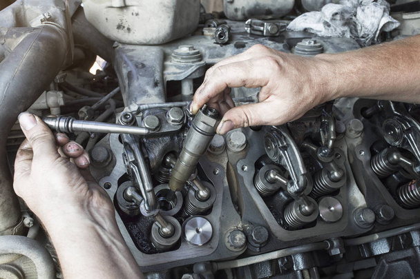 Mechaniker repariert einen LKW. Einstellung der Ventile des Dieselmotors. Ersatzdüsen. - Foto, Bild